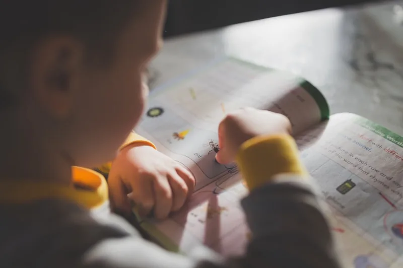 A student highlighting work in a workbook