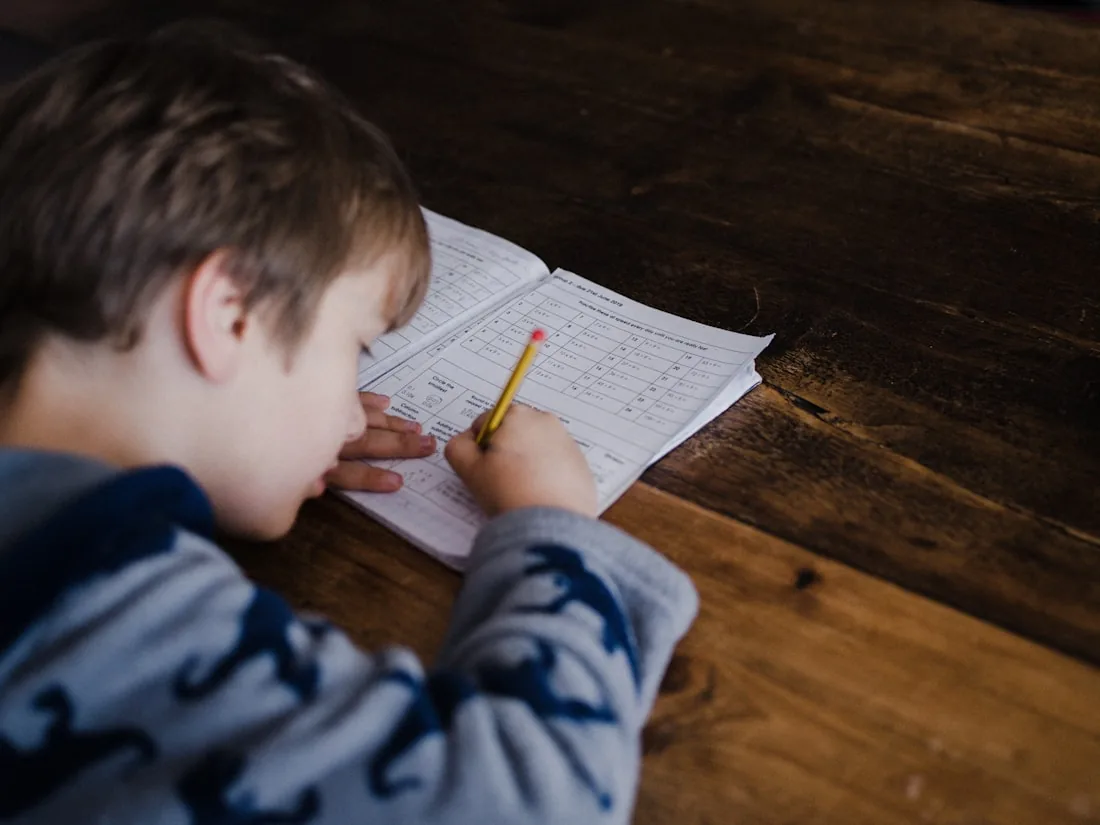 A child working through math in a workbook